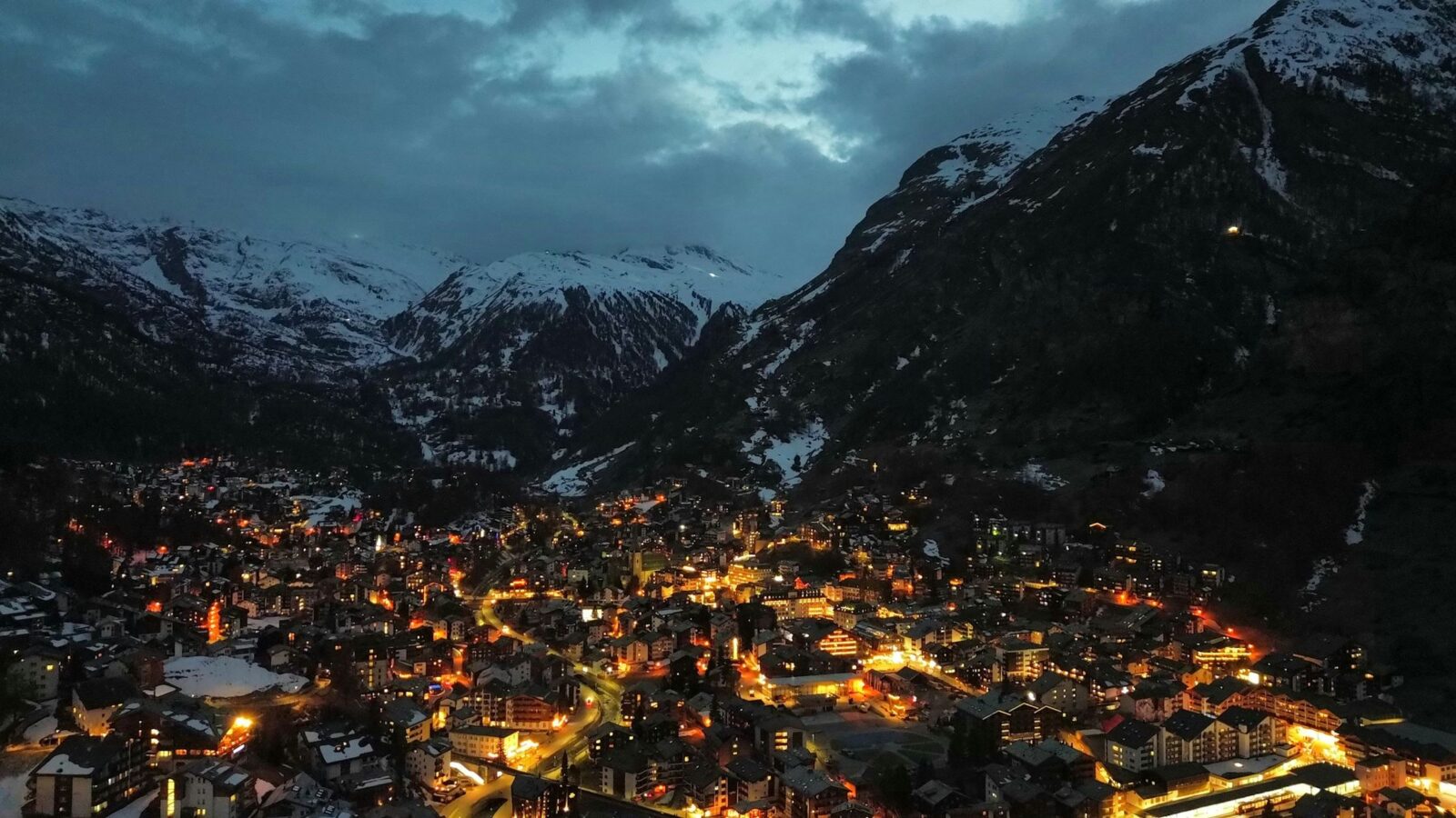 Paese alpino illuminato nella valle innevata all'ora blu